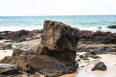 Okyanusa karşı karanlık deniz taşları ve bulutlu gökyüzü manzarası. Doğayı korumuş. Salvador, Brezilya