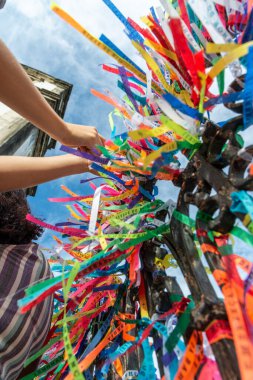 Salvador, Bahia, Brezilya - 27 Aralık 2019: Katolikler renkli kurdeleleri Salvador, Bahia 'daki Sinyor do Bonfim Kilisesi' nin kapısında hediye olarak bağlarken görüldü..