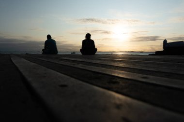 Salvador, Bahia, Brazil - September 14, 2024: People in silhouette are seen enjoying the sunset sitting on the pier at Porto da Barra beach, in the city of Salvador, Bahia. clipart