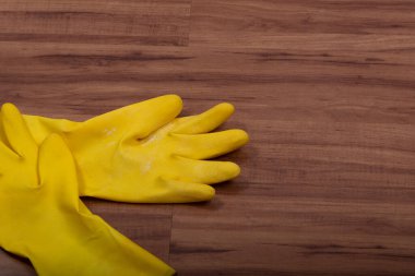 Ahşap arka planda izole edilmiş bir çift sarı kauçuk temizlik eldiveni..