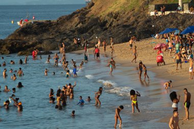 Salvador, Bahia, Brezilya - 21 Aralık 2019: İnsanlar Salvador, Bahia 'da yaz aylarında gün batımında Porto da Barra plajında eğlenirken ve banyo yaparken görülüyor.