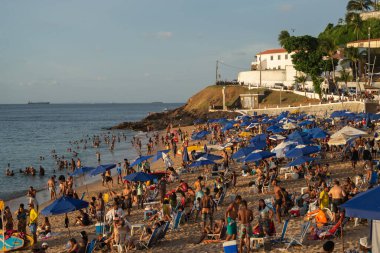 Salvador, Bahia, Brezilya - 21 Aralık 2019: Salvador, Bahia yazında gün batımında turist ve banyocularla dolu Porto da Barra plajı manzarası.