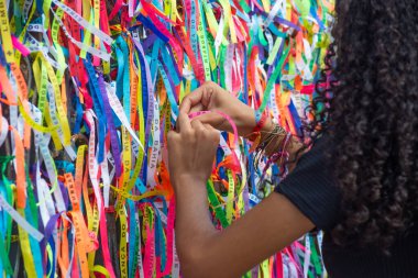 Salvador, Bahia, Brezilya - 27 Aralık 2019: Turistler Salvador, Bahia 'daki Sinyor do Bonfim Kilisesi' nin kapısında renkli hatıra kurdeleleri bağlarken görüldü..