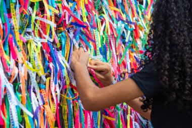 Salvador, Bahia, Brezilya - 27 Aralık 2019: Turistler Salvador, Bahia 'daki Sinyor do Bonfim Kilisesi' nin kapısında renkli hatıra kurdeleleri bağlarken görüldü..