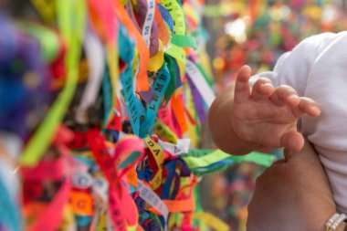 Salvador, Bahia, Brezilya - 27 Aralık 2019: Bir çocuğun eli, Salvador, Bahia 'daki Sinyor do Bonfim kilisesinin renkli kurdelelerine dokundu.