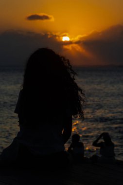 Salvador, Bahia, Brezilya - 22 Ekim 2024: Tanımlanamayan insanlar, siluet içinde, Bahia 'nın Salvador kentindeki Porto da Barra' da günbatımının keyfini çıkarıyorlar..