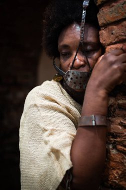 Siyah bir kadın zincirlenmiş ve ağzında demir bir maskeyle yüzü tuğladan bir duvara yapışmış. Brezilya 'da kölelik. Köle Anastacia 'yı temsil ediyorum..