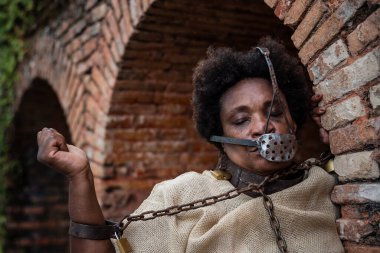 Köle gibi giyinmiş, ağzında demir bir maskeyle koluyla zincirlenmiş siyah bir kadının portresi. Brezilya 'da kölelik. Köle Anastacia 'nın temsilcisi.