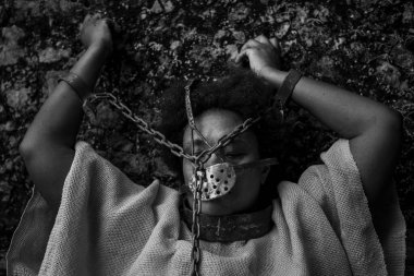 Ağzında ve boynunda demir bir maske olan kolları havada bir kadının siyah beyaz portresi. Brezilya 'da kölelik. Köle Anastacia 'nın temsilcisi.