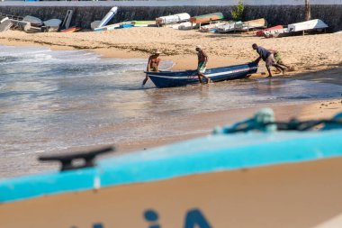 Salvador, Bahia, Brezilya - 21 Eylül 2019: Balıkçılar Rio Vermelho sahilinde bir balıkçı teknesini denize iterken görüldü. Salvador şehri, Bahia.