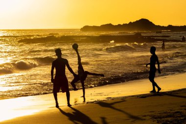 Salvador, Bahia, Brezilya - 06 Aralık 2019: İnsanlar gün batımında Bahia 'nın Salvador kentindeki Farol da Barra plajında futbol oynarken görüldü..
