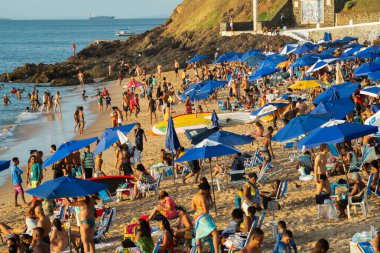 Salvador, Bahia, Brezilya - 21 Aralık 2019: Salvador, Bahia yazında gün batımında turist ve banyocularla dolu Porto da Barra plajı manzarası.
