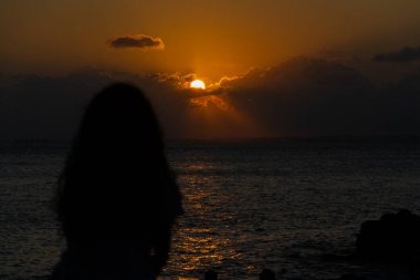 Salvador, Bahia, Brezilya - 22 Ekim 2024: Tanımlanamayan siluetli insanlar Porto da Barra 'da dramatik günbatımının tadını çıkarın. Salvador, Bahia.