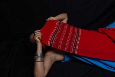 Güzel, olgun bir kadının portresi. Vücudunu kırmızı bir bezle kaplamış. Kameraya poz veriyorum. Siyah bir arkaplanda izole edilmiş.