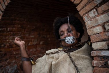 Köle gibi giyinmiş, ağzında demir bir maskeyle koluyla zincirlenmiş siyah bir kadının portresi. Brezilya 'da kölelik. Köle Anastacia 'nın temsilcisi.