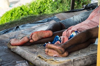 Bir şilte ve plastik üzerinde uyuyan iki kişinin bacakları ve ayakları. Evsiz insanlar. Salvador, Brezilya.