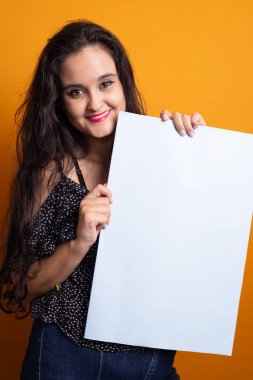 Elinde boş bir poster tutan kadın gülümseyip kameraya bakıyor. sarı arkaplanda izole.