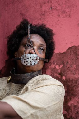 Köle gibi giyinmiş, ağzında demir bir maskeyle zincirlenmiş siyah bir kadının yakın plan portresi. Brezilya 'da kölelik. Köle Anastacia 'nın temsilcisi.