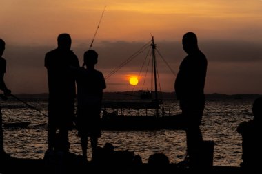 Salvador, Bahia, Brezilya - 16 Kasım 2019: İnsanlar, siluet içinde, Salvador, Bahia şehrinde dramatik günbatımının keyfini çıkarırken görülüyor.
