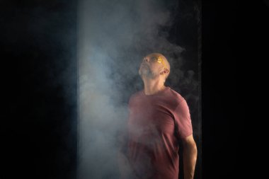 Kel ve sakallı bir adam sarı koruyucu gözlüklü, yukarı bakıyor. Koyu dumanlı arka planda izole edilmiş. Güney Amerikalı..