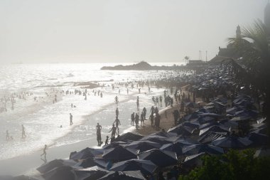 Salvador, Bahia, Brezilya - 05 Ocak 2025: Denizde yıkanan turistlerle dolu Farol da Barra plajının manzarası. Salvador, Bahia.