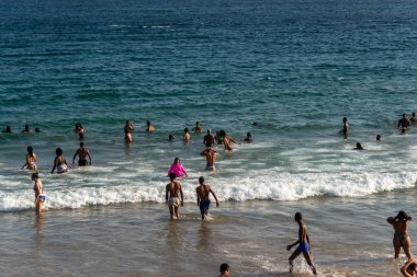 Salvador, Bahia, Brezilya - 05 Ocak 2025: İnsanlar Farol da Barra plajında güçlü öğleden sonra güneşi altında eğlenirken görülüyor. Salvador, Bahia. 