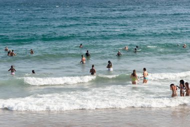 Salvador, Bahia, Brezilya - 05 Ocak 2025: İnsanlar güçlü güneş ışığı altında Farol da Barra plajında eğlenirken görülüyor. Salvador, Bahia. 