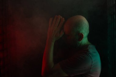 Eli kafasında kel ve sakallı bir adam. Siyah dumanlı arka planda, renkli ışıklarla izole edilmiş. Güney Amerikalı..