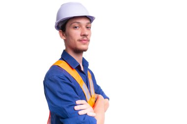 Beyaz kasklı ve parlak yelek giyen genç mimar kollarını kavuşturmuş fotoğraf için poz veriyor. Beyaz arka planda izole edilmiş. Güvenlik ekipmanları.