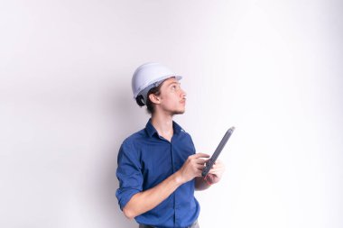 Genç mimarın portresi, beyaz kask takıyor, dizüstü bilgisayarla çalışıyor ve yan bakıyor. Beyaz arka planda izole edilmiş. Güvenlik ekipmanları.