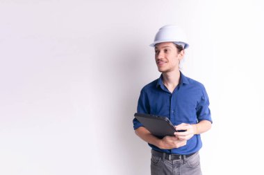 Genç mimarın portresi, beyaz kask takıyor, dizüstü bilgisayarla çalışıyor ve yan bakıyor. Beyaz arka planda izole edilmiş. Güvenlik ekipmanları.