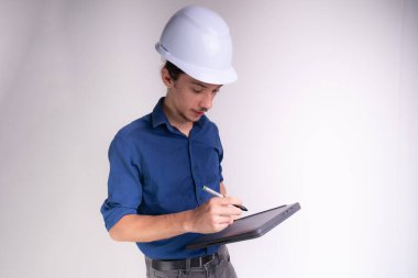 Tabletle çalışan beyaz kasklı genç bir mimarın portresi. Beyaz arka planda izole edilmiş. Güvenlik ekipmanları.