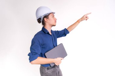 Genç mimarın portresi, beyaz kask takıyor, dizüstü bilgisayarla çalışıyor ve yan bakıyor. Beyaz arka planda izole edilmiş. Güvenlik ekipmanları.