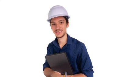 Beyaz kask ve parlak yelek giyen genç bir mimar dizüstü bilgisayar tutuyor ve kameraya bakıyor. Beyaz arka planda izole edilmiş. Güvenlik ekipmanları.