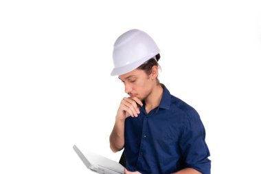 Genç mimar beyaz kask takıyor, oturuyor ve tabletle çalışıyor. Beyaz arka planda izole edilmiş. Güvenlik ekipmanları.