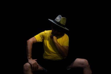 Olgun bir adam, 50 'li yaşlarda, sarı gömlek, güneş gözlüğü ve şapka takıyor, oturuyor, fotoğraf için poz veriyor. Sakin biri. Brezilya