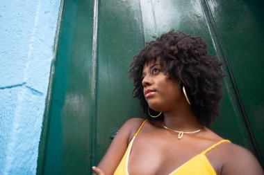 Yeşil kapıya karşı afro saçlı güzel bir kadının yakın plan portresi. Yolculuktaki mutlu insan..