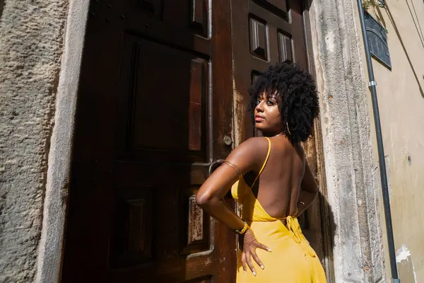 Sarı elbiseli güzel bir kadının portresi eski kahverengi ahşap kapının yanında duruyordu. Mutlu insan seyahat konsepti.