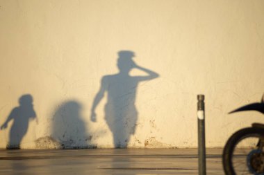 Kimliği belirsiz üç kişinin gölgesi öğleden sonra güneşinin altında bir evin duvarına yansıyor. Brezilya