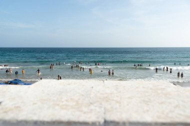 Salvador, Bahia, Brezilya - 05 Ocak 2025: İnsanlar güçlü güneş ışığı altında Farol da Barra plajında eğlenirken görülüyor. Salvador, Bahia. 