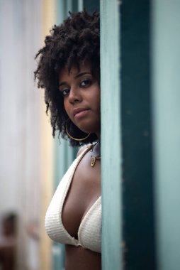 Duvara yaslanmış fotoğraf için poz veren güzel siyah güçlü kadın. Gülümseyen ve güçlü bir insan. Brezilya