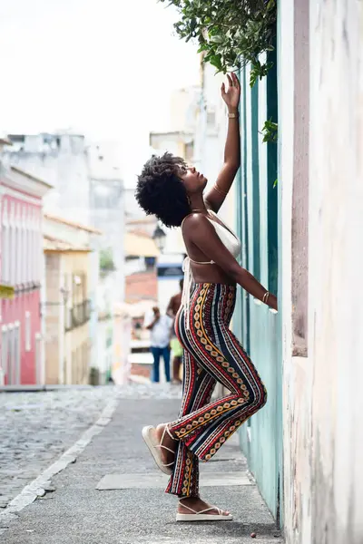 Eski bir duvara yaslanmış fotoğraf için poz veren güzel bir kadın. Gülümseyen ve güçlü bir insan. Brezilya