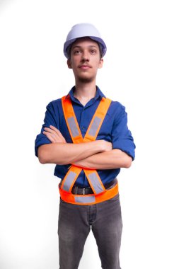 Beyaz kasklı ve parlak yelek giyen genç mimar kollarını kavuşturmuş fotoğraf için poz veriyor. Beyaz arka planda izole edilmiş. Güvenlik ekipmanları.