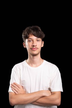 Beyaz gömlek giyen, gülümseyen, kollarını kavuşturup fotoğraf için poz veren genç yakışıklı bir adam. Siyah arka planda izole edilmiş. Stüdyo çekimi