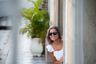 Beyaz elbiseli, güneş gözlüklü, kameraya bakan güzel bir kadın. Seyahatte mutlu bir insan. Güney Amerika