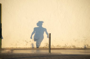 Kimliği belirsiz bir kişinin gölgesi bir evin duvarına yansıtılıyor. Öğleden sonra güneşinin altında. Brezilya