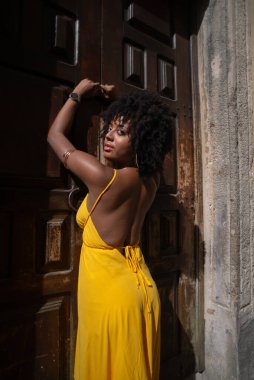 Sarı elbiseli güzel bir kadının portresi eski kahverengi ahşap kapının yanında duruyordu. Mutlu insan seyahat konsepti.