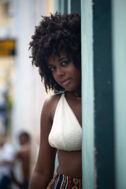 Duvara yaslanmış fotoğraf için poz veren güzel siyah güçlü kadın. Gülümseyen ve güçlü bir insan. Brezilya