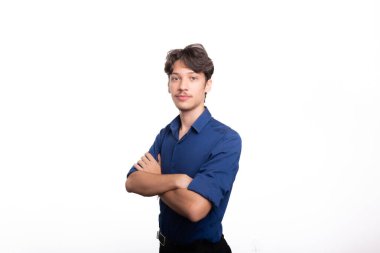 Kollarını kavuşturup kameraya bakan mavi gömlekli genç ve yakışıklı bir öğrenci. Beyaz arka planda izole edilmiş. Kendine güvenen biri. Profesyonel konsept.