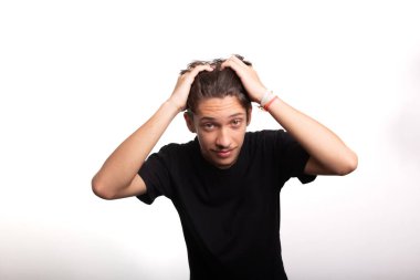 Siyah gömlekli yakışıklı genç adam, gülümsüyor, kameraya bakıyor ve saçlarına el koyuyor. Beyaz arkaplanda izole.